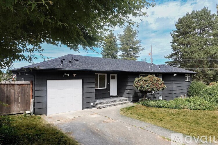 A house with a garage and a driveway is surrounded by greenery.