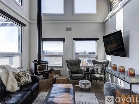 A living room with a black leather couch and a wood burning stove.