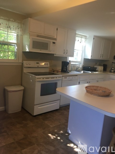 A kitchen with white cabinets and a white island.