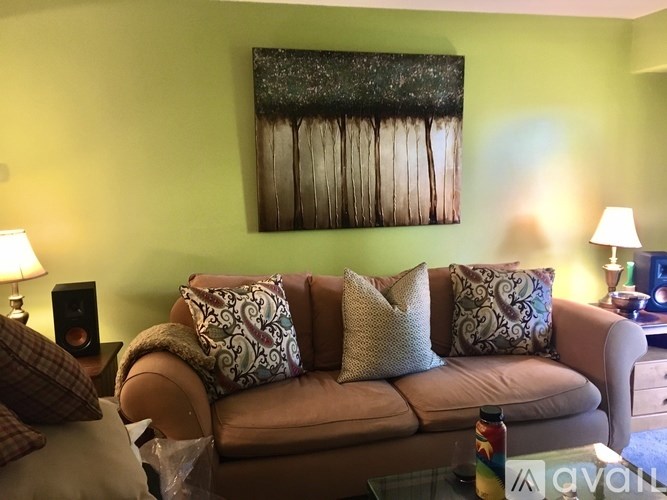 A living room with a couch, a painting, and a speaker.