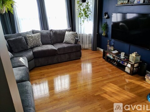 A living room with a grey sofa and a wooden floor.