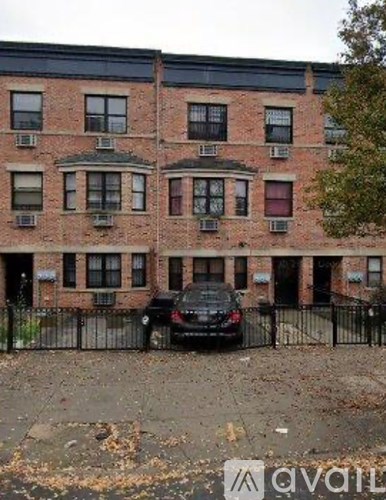 A black car is parked in front of a brick building.