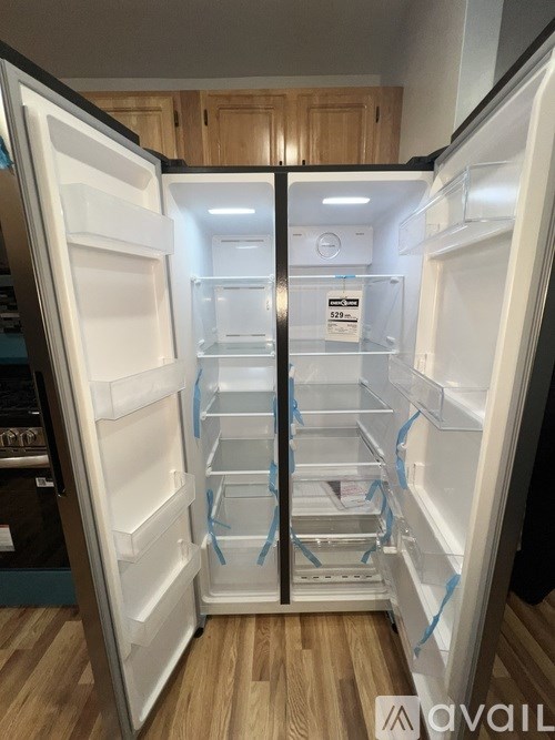 A white refrigerator with its door open and a sticker on the door.