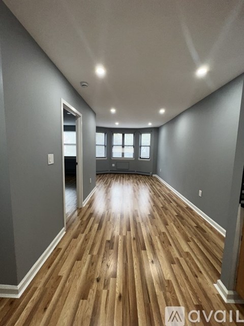 A spacious room with wooden flooring and a large window.