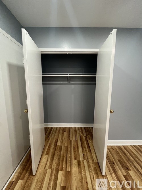 A white closet with a wooden floor and a grey wall.