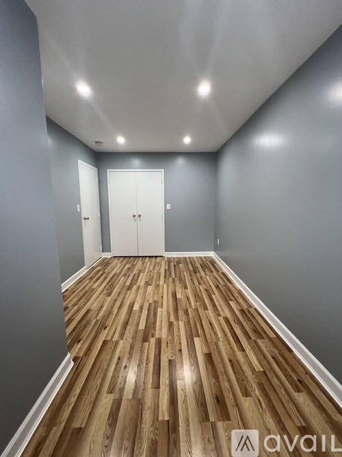 A room with wooden flooring and two white doors.