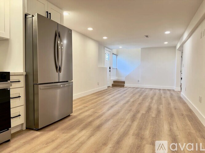 A modern kitchen with a stainless steel refrigerator and wooden flooring.