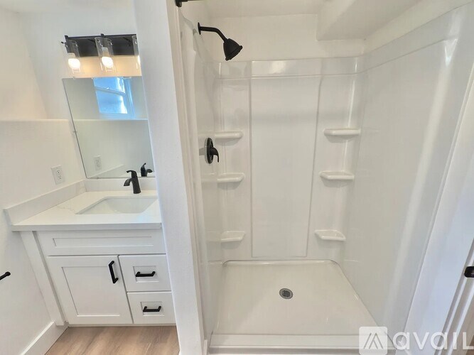 A white bathroom with a sink, mirror, and shower.