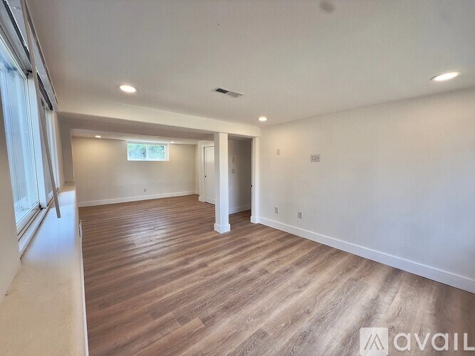 A spacious room with wooden flooring and white walls.