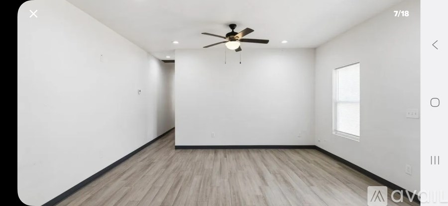 A spacious room with a ceiling fan and wooden flooring.