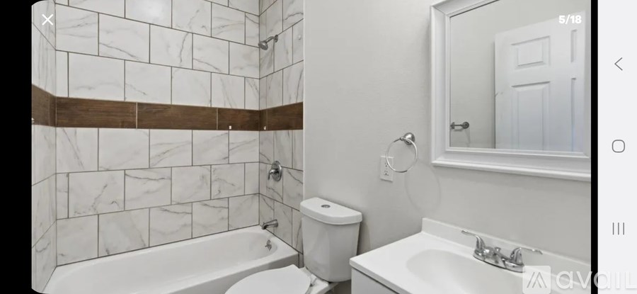 A white bathroom with a marble tile wall and a white toilet.