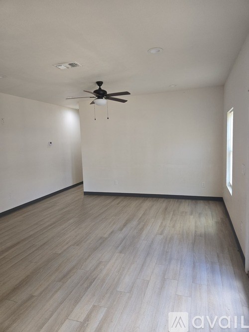 A room with a ceiling fan and light, and a window with sunlight coming in.