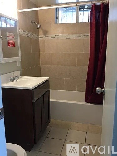 A bathroom with a white sink and a red shower curtain.