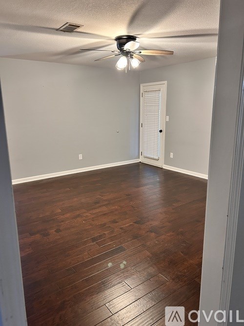 A room with a ceiling fan and wooden flooring.