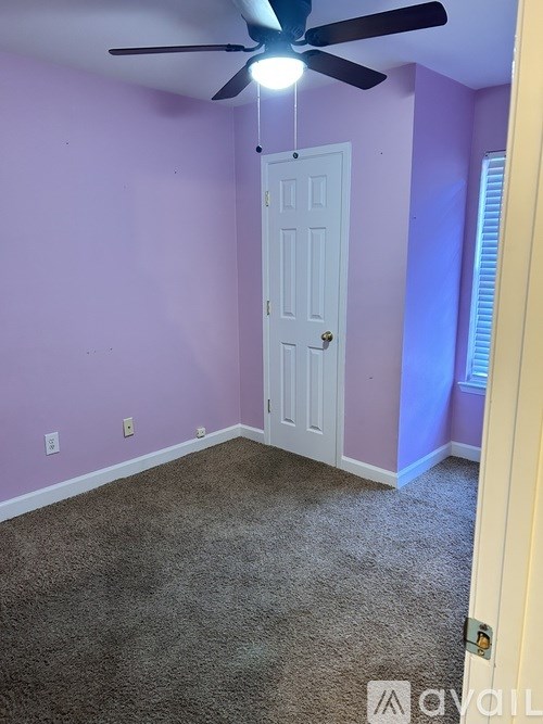 A room with a white door and a ceiling fan.