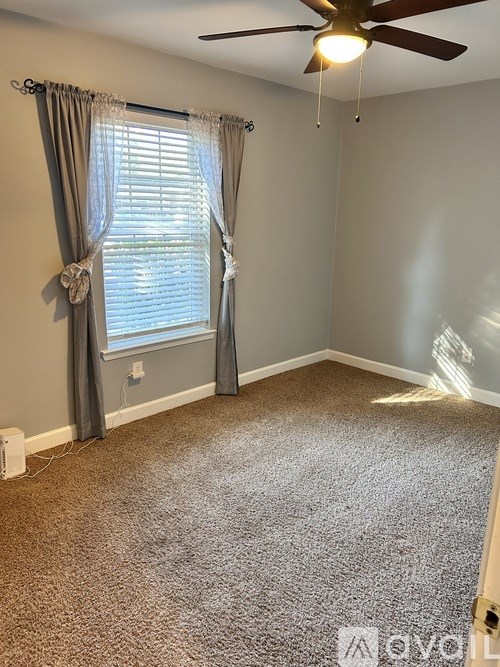 A room with a ceiling fan and carpeted floor.