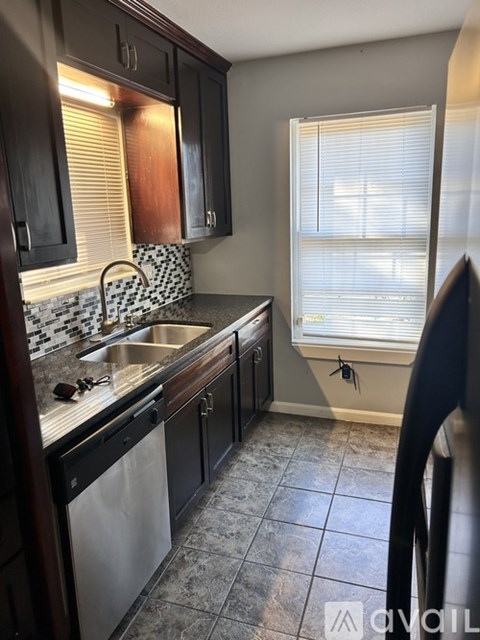 A kitchen with dark wood cabinets and a white sink.