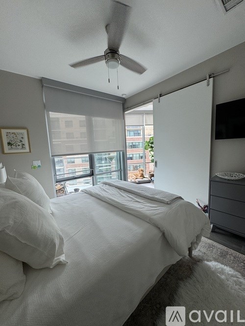 A bedroom with a bed, a ceiling fan, and a window with blinds.