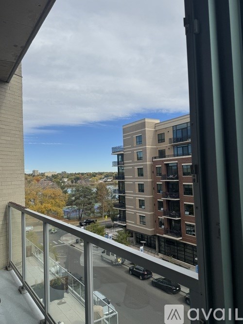 A view from a balcony overlooking a parking lot and a multi-story building.