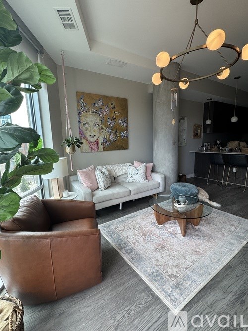 A living room with a brown leather chair, a white sofa, and a large abstract painting on the wall.