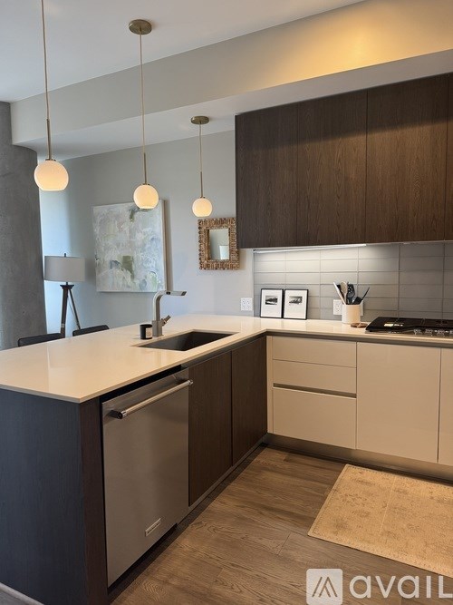 A modern kitchen with a white countertop and dark brown cabinets.