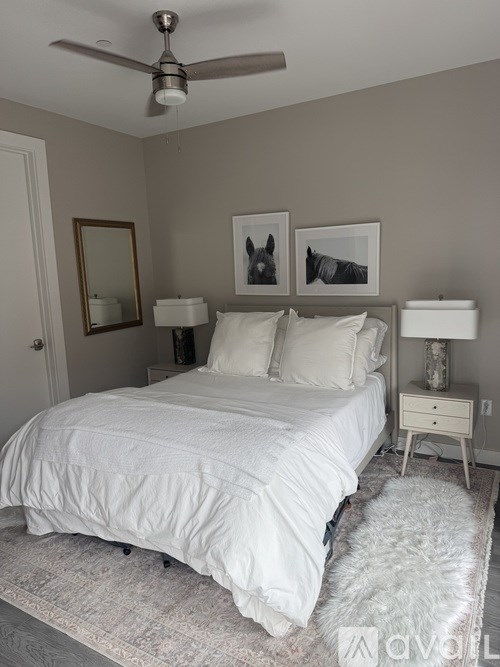 A bedroom with a white bed and a ceiling fan.