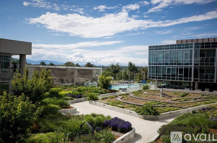 A modern building with a glass facade is surrounded by a landscaped garden.