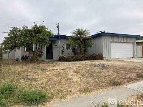 A house with a garage and a tree in front.