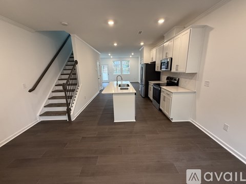 A kitchen with white cabinets and a black refrigerator.