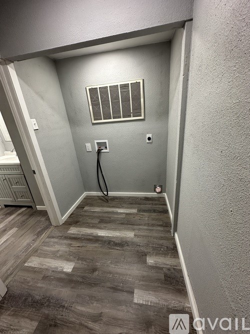 A hallway with a wooden floor and a window with blinds.