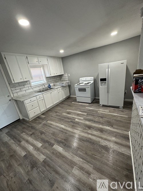 A kitchen with white cabinets and a wooden floor.