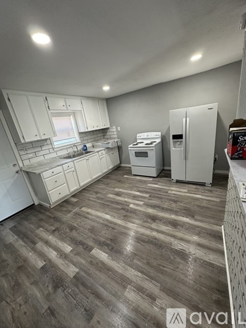 A kitchen with white cabinets and a wooden floor.
