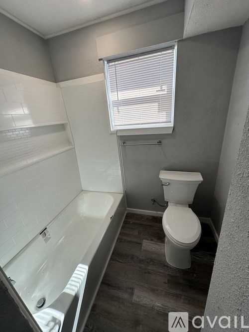 A white toilet sits in a bathroom next to a bathtub.