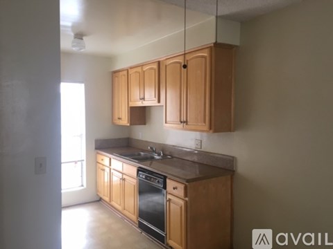 A kitchen with wooden cabinets and a black dishwasher.