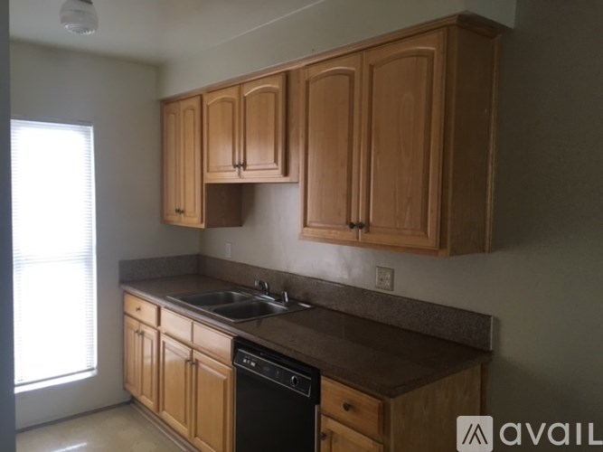 A kitchen with wooden cabinets and a black dishwasher.
