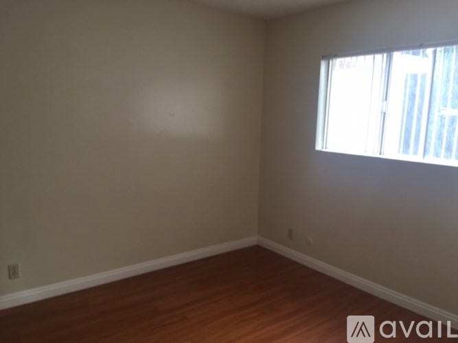 Empty room with wooden floor and a window letting in sunlight.