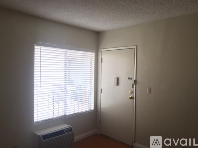A room with a white door, a window with blinds, and a wall-mounted air conditioner unit.