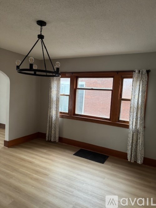 A room with a wooden floor and a window with curtains.