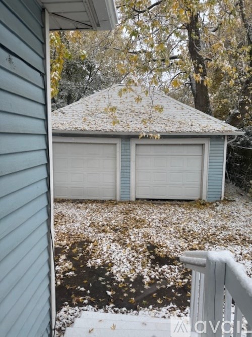 A house with a grey roof and two white garage doors.