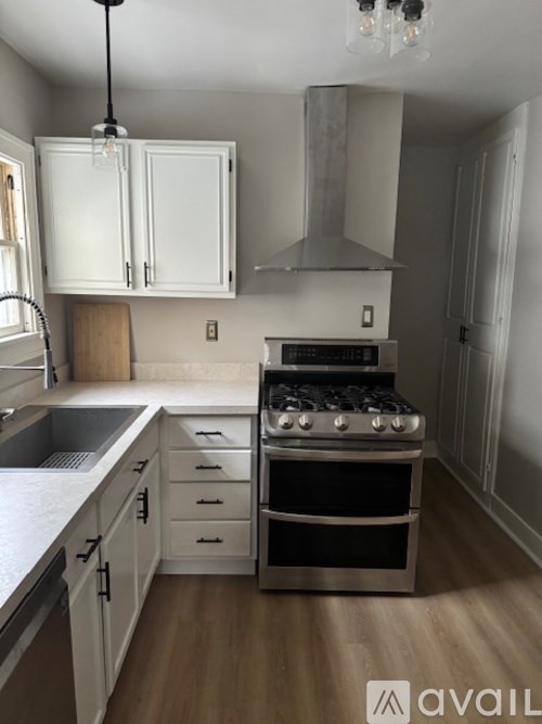 A kitchen with a stove, sink, and cabinets.