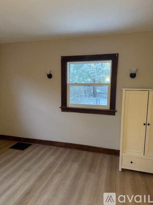 A room with a window and a wooden floor.