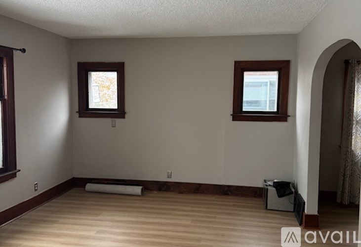 A room with wooden floors and two windows.