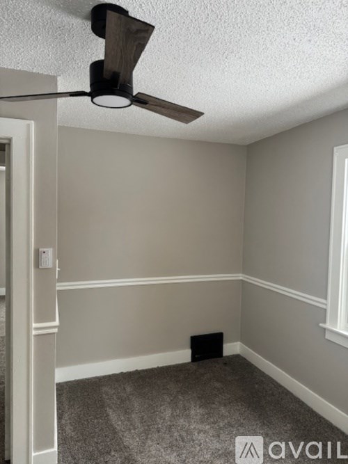 A room with a ceiling fan and a carpeted floor.