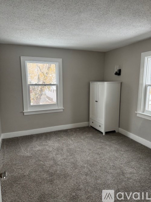 A room with a window and a white cabinet.