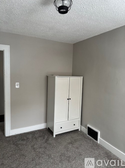 A white cabinet with two doors and two drawers is in a room with grey carpeting.