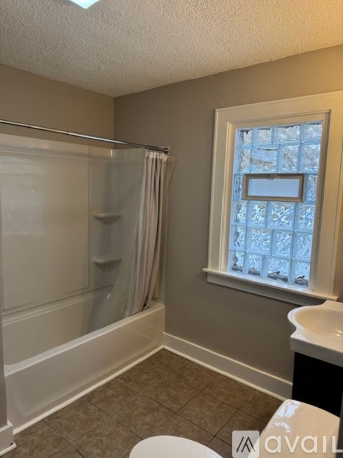A bathroom with a glass shower door and a window with a view of a snowy landscape.