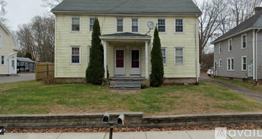 A yellow house with a red door and a mailbox on the front porch.