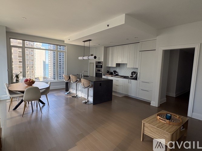 A modern kitchen with white cabinets and a wooden floor.