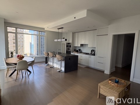 A modern kitchen with white cabinets and a wooden floor.
