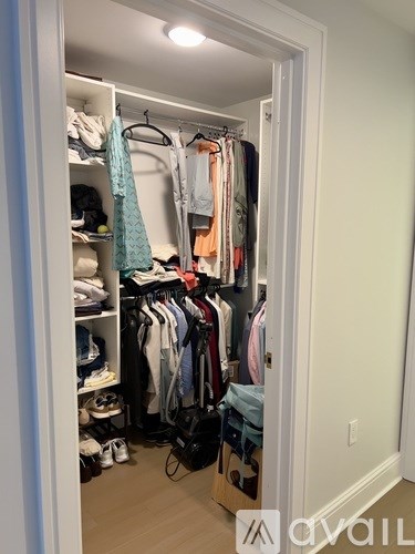 A white closet with clothes and shoes.